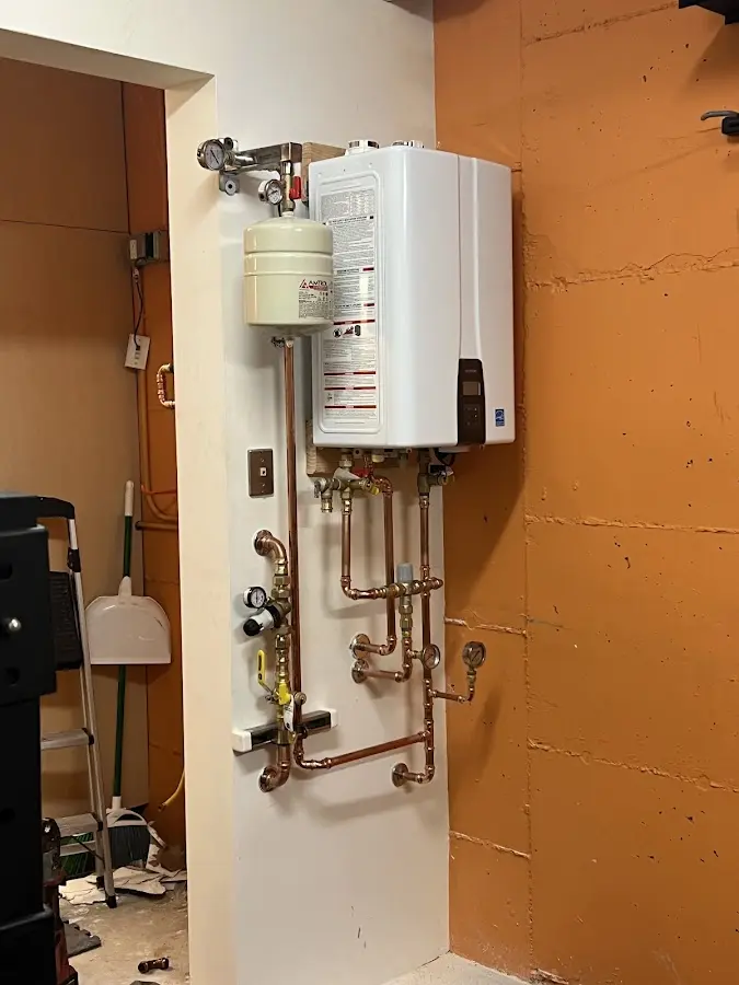 Plumbing technician inspecting water heater connections in Ellery